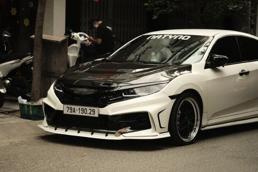 A sleek, custom-modified white sports car parked on an urban street. Perfect for enthusiasts.
